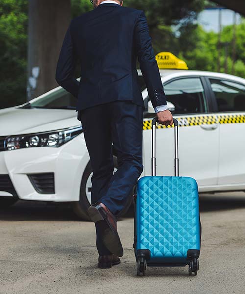 man in a suit walking toward a taxi